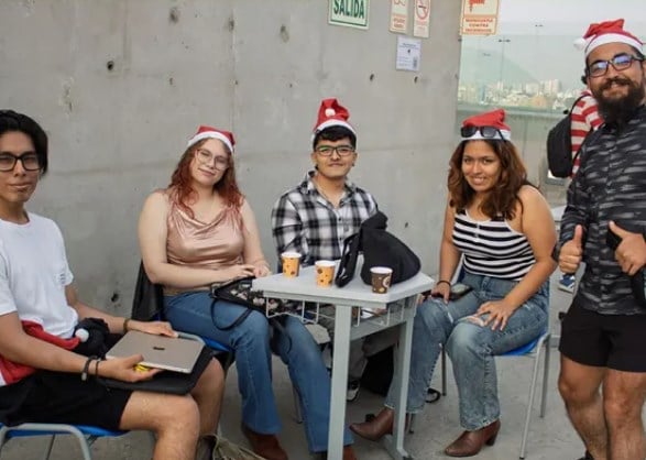 Grupo de asistentes sentados alrededor de una mesa con vasos de chocolate