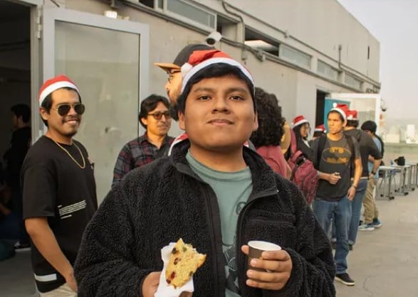 Un asistente sostiene su porción de panetón y su vaso de chocolate
