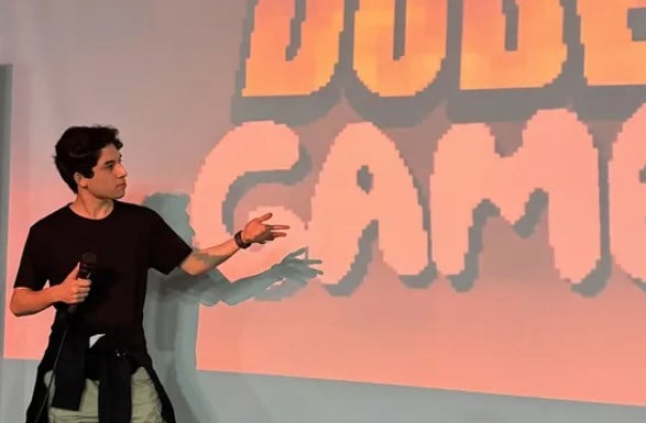 Un desarrollador presenta Dude Game ante la pantalla con el logotipo del juego
